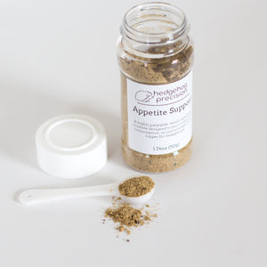 A spoonful of Appetite Support powder next to a small bottle of the product