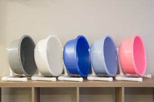 A gray, white, pearl blue, light blue, and pink Hedgehog Precision exercise wheel lined up on a tabletop. 