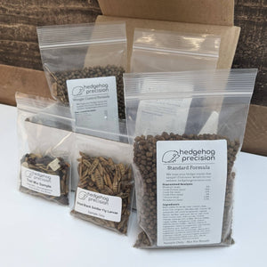 Various samples of pet hedgehog foods and insect treats on a white box. 